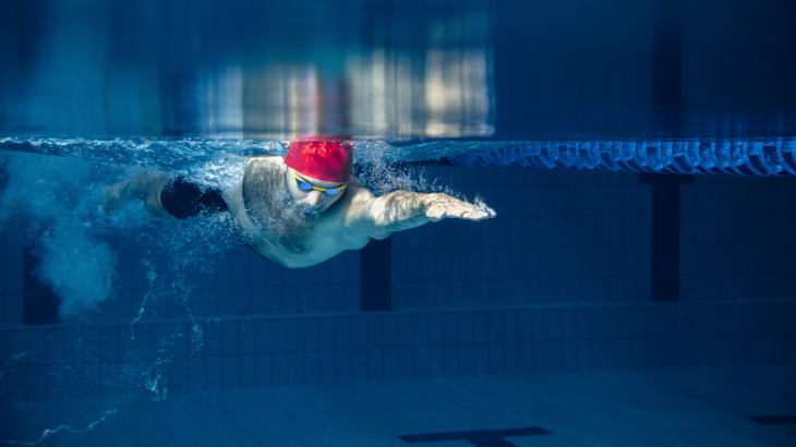 one male swimmer practicing and training at pool