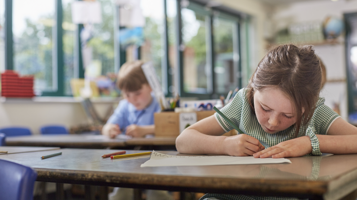 schoolgirl writing in classroom lesson in primary