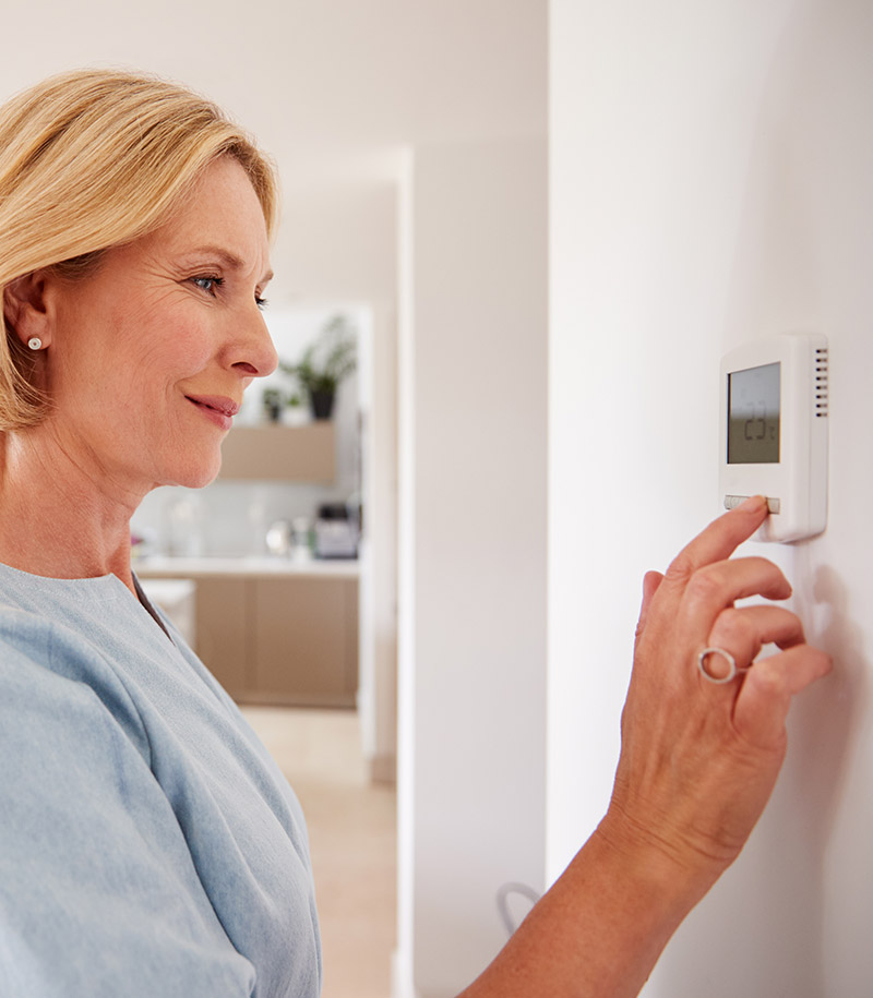Women adjusting thermostat